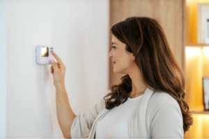Woman adjusting indoor thermostat
